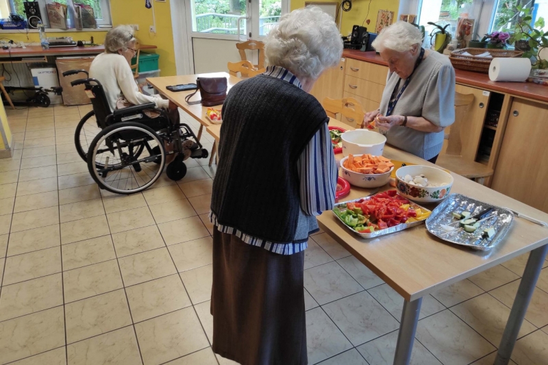 Mieszkanki tworzące szaszłyki,, w tle miłośniczka tableta.